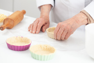 Obraz na płótnie Canvas Senior woman preparing dough for a delicious cheese and ham tartlet