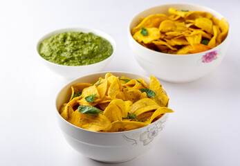 Bowls of Unripe Plantain chips with basil leaves and Pesto sauce Close up view