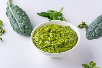 Vegetarian Pesto sauce in a white ceramic bowl with Tuscan Kale, basil and parsley 
