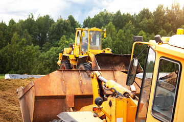 A yellow bulldozer is compacting a green mass of cut grass. 