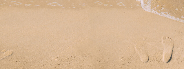 Footprints on the wet sand by the wave. Top view of the banner