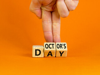 Doctor day symbol. Doctor turns wooden cubes with words 'Doctors day'. Beautiful orange background. Doctor day and medical concept. Copy space.