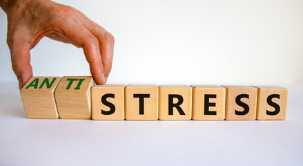 Antistress vs stress symbol. Doctor turns cubes and changes the word stress to anti stress. Beautiful white table, white background. Medical, psychological, antistress vs stress concept. Copy space.