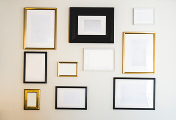 Empty gold and black photo and picture frames on white wall, mock up for your photos or text, copy space modern design luxury decoration