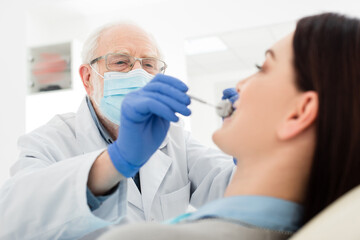 senior dentist making teeth examination of woman in dental chair.