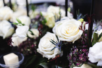 White roses and dark purple accents in floral centerpiece