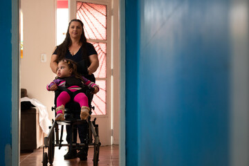 child with physical disability and mother arriving at home on wheelchair.