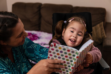 baby with physical disability smiling and happy with colorful book..