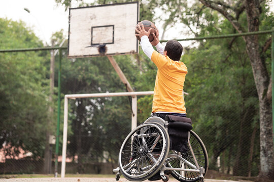 person in wheelchair throwing basketball in open court..