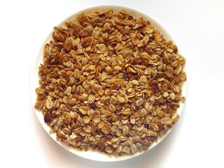 On white isolated background granola on plate, breakfast dish, snack. On the photo is a granule of oatmeal and honey. Application in the packaging of products as well as flyers and the articles