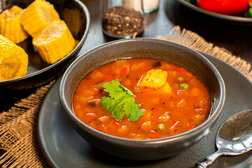 Mexican tomato, bean, bell pepper soup and corn in the dark bowl.