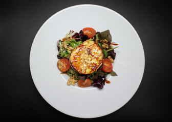 Ensalada de queso de cabra caramelizado con lechugas variadas en plato blanco