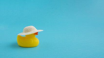 Yellow rubber duck with a straw hat on a blue background. Summer vacation trip. Minimal concept.