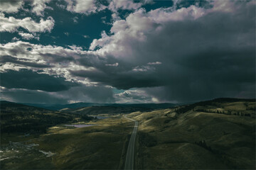 Picturesque view of an empty road surrounded by hills under a cloudy sky