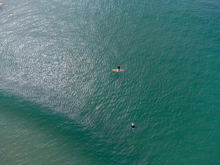 Surfers and paddle boarders in a turquoise sea aerial uk cornwall 