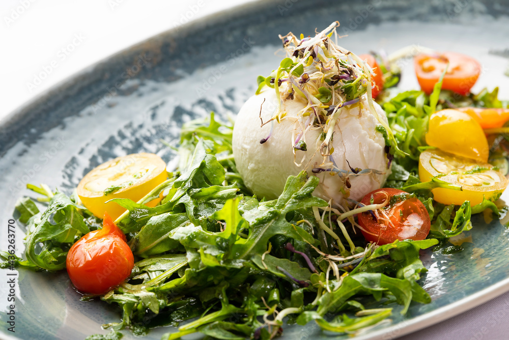 Wall mural mozzarella ball and vegetable salad on a blue plate