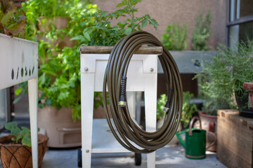 A drinking water safe garden hose sits on an elevated planter, made from 100% lead-free, food-grade...