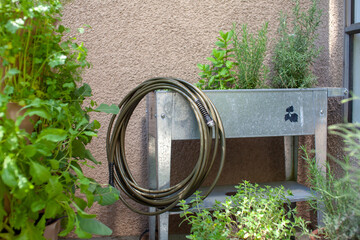 A drinking water safe garden hose sits on an elevated planter, made from 100% lead-free, food-grade...
