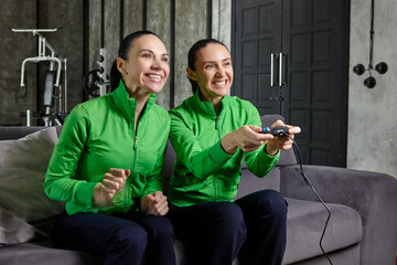 Adult women play video games using joystick from game console.