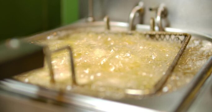 Cooking oil boiling and bubbling in fryer for deep frying dishes in a professional restaurant kitchen. 