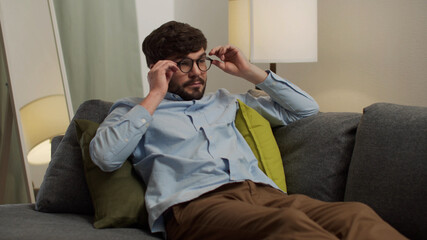 White man with glasses resting lying on the couch