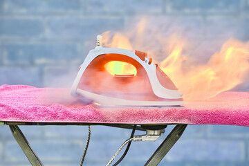 An overheated household appliance is burned, forgotten electric iron caught fire on ironing board.