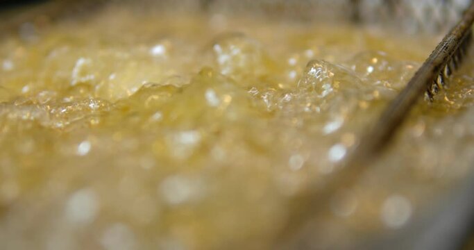 Cooking oil boiling and bubbling in fryer for deep frying dishes in a professional restaurant kitchen. 