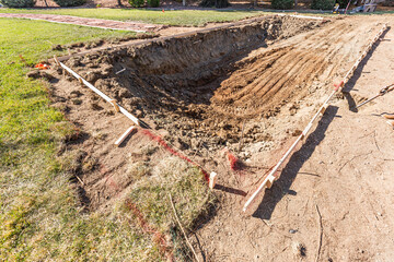 Freshly Dug Hole In Yard Preparing For Swimming Pool Installation