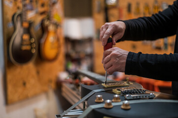 Black electrical guitar in repair service shop with a hands of a guitar luthier