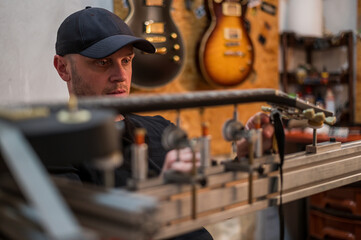 Guitar in repair service shop with a guitar luthier which fixes and tightens it
