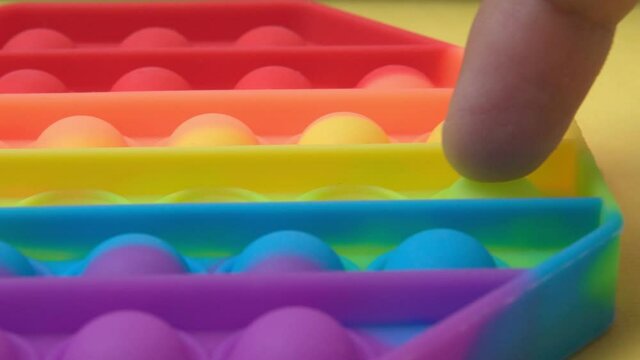Colorful antistress sensory toy fidget push pop it. On a yellow background