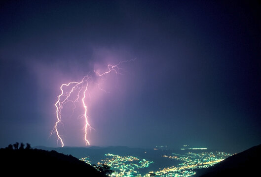 Fotografia noturna de raio com as luzes de Poços de Caldas, Minas Gerais. Representa a força da natureza.