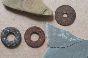 abstract composition with various isolated stones and rusty metallic washers on paper -...