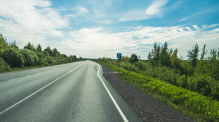 Fototapeta premium The road among the Karelian taiga. Pine forest on the side of the road. Trip to Karelia. Highway among the trees. Driving on a trip to beautiful places. Karelia. Day.