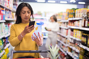 Shopper using smartphone scans qr code on label in grocery supermarket