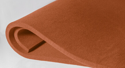 two sheets of orange spongy foam material with curved folds isolated on a white background