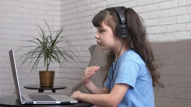Stay on online lessons. A little girl listen a lesson in headphones at home. A concept of education on distance.