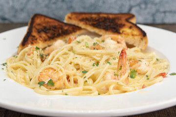 Shrimp scampi in buttery sauces and pasta served on a plate with grilled toast for a hearty appetite