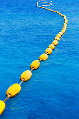 curves line of yellow buoys in clear blue sea