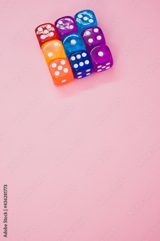 Sticker Vertical shot of a cube made of colorful dice isolated on a pink background