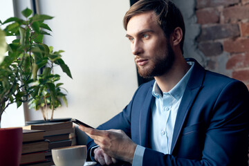 business man sitting at a table in a cafe breakfast with a phone in his hands