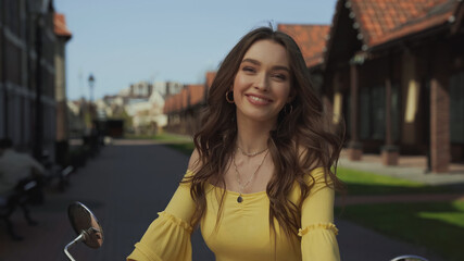 happy young woman with wavy hair smiling outside.