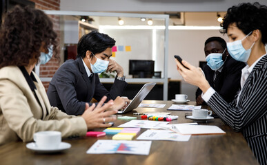 Multiracial mixed race businesspeople group working with concentration  at office, wearing face masks as new normal to protect or prevent virus in pandemic crisis, using laptop and job discussion.