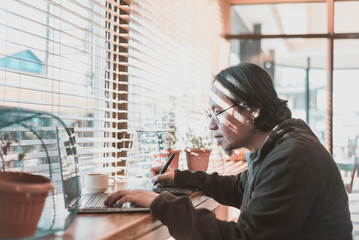 A middle aged asian graphic designer freelancer with a laptop and drawing tablet. Working remotely...