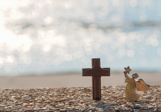 Angel shape on gravel floor in bokeh of sea .Angel and miracle. Faith in God. Pray for you. Miracle from heaven. Believe in goddess. Christianity background concept.