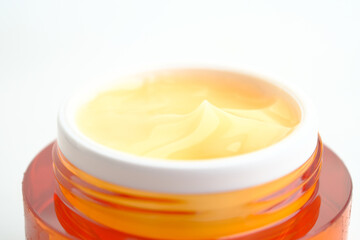 Close up of face cream in a orange container isolated on white