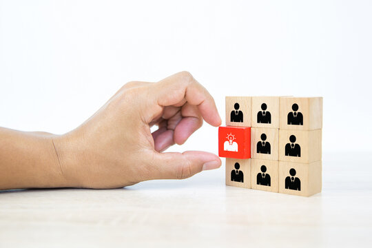 Hand choosing people icon with head light bulb on cube wooden toy block stacked. Concepts of human resources personnel selection and person organization job fit and employees performance.