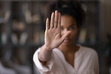 Close up focus on female mixed race palm hand showing stop sign, serious african american woman protesting against bullying in society, sexual or racial discrimination, denying family abuse indoors. - obrazy, fototapety, plakaty