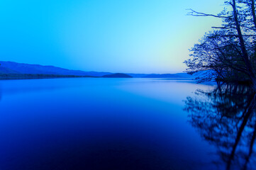 青く染まる夜明けの湖畔の風景。