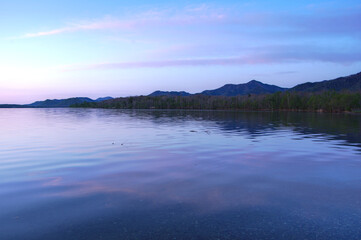 Fototapeta na wymiar 薄い青に染まるトワイライトの湖と空。